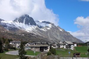 A mountain with snow on top of it and houses in the background.